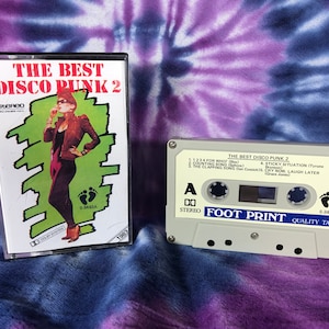 May include: A cassette tape labeled "The Best Disco Punk 2" with the song titles "1, 2, 3, 4 For Who?", "Counting Sound", "The Clapping Sound", "Sticky Situation", "Cry Now, Laugh Later". The cassette tape is from the band "Foot Print" and is a quality tape.
