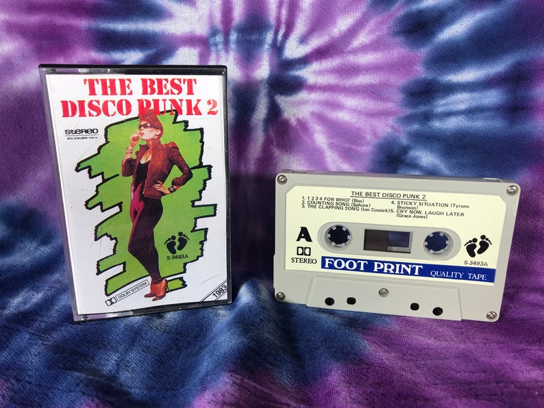 May include: A cassette tape labeled "The Best Disco Punk 2" with the song titles "1, 2, 3, 4 For Who?", "Counting Sound", "The Clapping Sound", "Sticky Situation", "Cry Now, Laugh Later". The cassette tape is from the band "Foot Print" and is a quality tape.