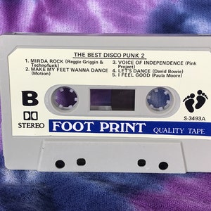 May include: A white cassette tape with the title "The Best Disco Punk 2" and the text "Foot Print Quality Tape" printed on it. The cassette tape has a black footprint symbol and the number "S-3493A" printed on it.