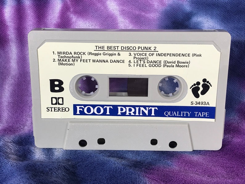 May include: A white cassette tape with the title "The Best Disco Punk 2" and the text "Foot Print Quality Tape" printed on it. The cassette tape has a black footprint symbol and the number "S-3493A" printed on it.
