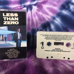 May include: Two cassette tapes from the "Less Than Zero" soundtrack. The first cassette case features the movie title and a photo of a man in a suit. The second cassette is white with song titles.