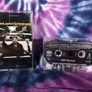 May include: A black cassette tape with the title "Fun Lovin' Criminals: Come Find Yourself" and the band's logo. The cassette tape is in a clear plastic case.