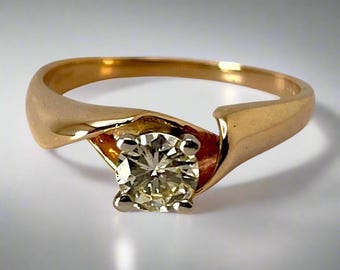 May include: A gold engagement ring with a single round diamond set in a twisted band.