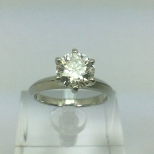 May include: A silver ring with a large, round, clear diamond.