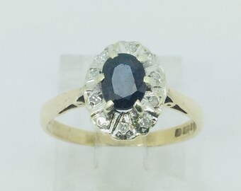May include: A gold ring with a dark blue oval sapphire surrounded by a halo of smaller diamonds.