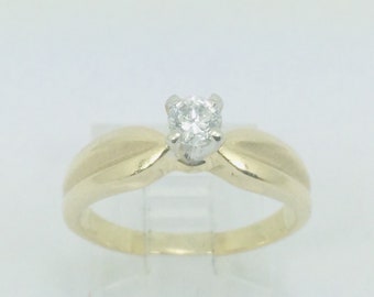 May include: A gold band engagement ring with a single round diamond in the center.