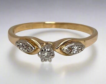 May include: A gold band ring with three small diamonds. The center diamond is larger than the two diamonds on either side.