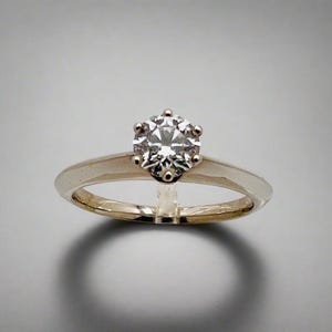May include: A gold engagement ring with a round, clear diamond.