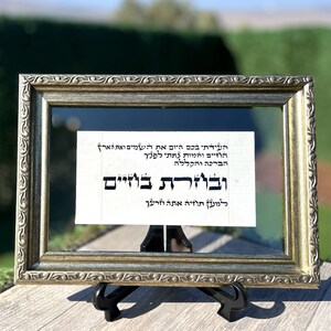 May include: A framed piece of paper with Hebrew text in black ink. The text reads: "העידתי בכם היום את השמים ואת הארץ הוזיים והמות נתתי לפניך הברכה והקללה ובוזרת בוזיים למען תוזיה אתה וזרעך"