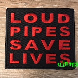 Puede incluir: Parche negro con texto bordado en rojo que dice "Loud Pipes Save Lives".