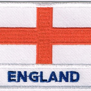Könnte beinhalten: Weißer gestickter Aufnäher mit einem roten Kreuz und dem Wort "ENGLAND" in blauen Buchstaben.