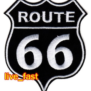 Könnte beinhalten: Schwarz-weiß gestickter Patch in Schildform. Der Patch zeigt den Text "ROUTE 66" in weiß.