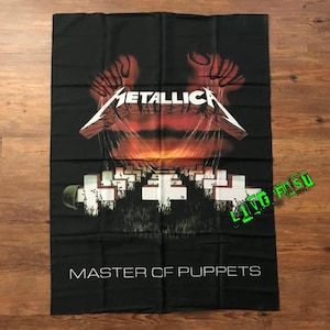 May include: Black rectangular banner featuring the band Metallica's logo in silver and the words "MASTER OF PUPPETS" in white. The design includes a red and orange sunset, white crosses, and stylized hands.