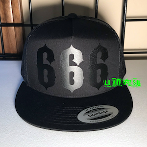 Op de afbeelding: Zwarte en zilveren truckercap met het nummer 666 in een gotisch lettertype. De pet is een snapback van het merk Yupoong.