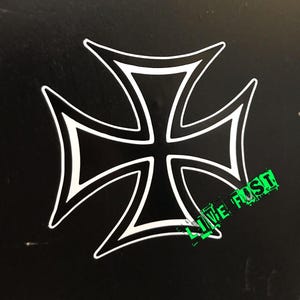 May include: A black iron cross with a white outline. The cross is a popular symbol in biker culture.