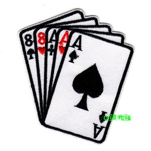 Puede incluir: Parche bordado con una mano de naipes. Las cartas incluyen un As de Picas, un As de Diamantes, un As de Corazones y un Ocho de Corazones. El parche tiene un fondo blanco con detalles en negro y rojo.