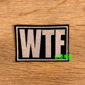 May include: A black and white embroidered patch with the word "WTF" in white letters on a black background.