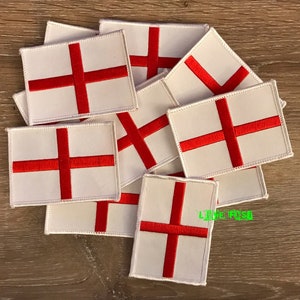 May include: A collection of rectangular patches featuring the flag of England. Each patch has a white background with a prominent red cross. The patches are neatly arranged, showcasing the design's simplicity and bold color contrast.