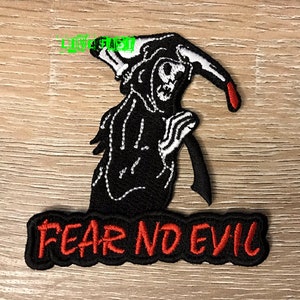 May include: Black embroidered patch featuring the Grim Reaper with a scythe and the text "FEAR NO EVIL" in red. The Grim Reaper is wearing a black hooded cloak with a white skeleton face and hands. The patch is on a wooden surface.