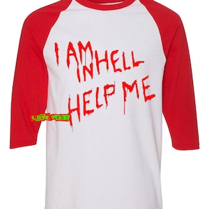 May include: A white and red baseball tee shirt with the text "I AM IN HELL HELP ME" printed in red dripping letters.