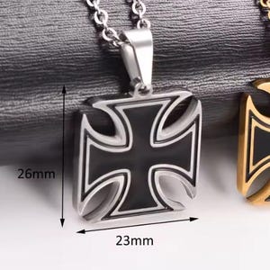 May include: A silver-toned iron cross pendant on a chain, featuring a black enamel inlay. The pendant measures 26mm in height and 23mm in width, as indicated by the black arrows and text labels visible on the image.