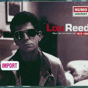May include: A CD cover featuring a black and white photo of Lou Reed, a musician, wearing sunglasses. The title "Lou Reed" is in red text and the text "Meer dan het beste van 1972-1986" is in black text. The text "HUMO selecteert" is in red text in the upper right corner. The text "IMPORT" is in red text in the lower left corner.