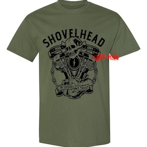 May include: A green t-shirt with a black graphic of a skull and crossbones with the text "SHOVELHEAD 1966-1984" and "IN SHOVEL WE TRUST".