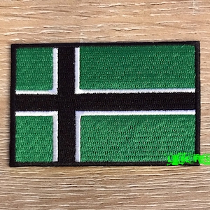 May include: Green, black, and white embroidered patch with a cross design.