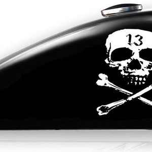May include: Black motorcycle gas tank with a white skull and crossbones graphic. The skull has the number "13" on its forehead.
