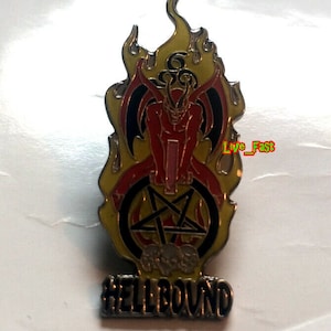 Puede incluir: Un pin de metal rojo y negro con una figura de diablo en llamas, un pentagrama y calaveras. El texto "HELLBOUND" está debajo de la figura. El texto "Live_Fast" está escrito en verde en la imagen.