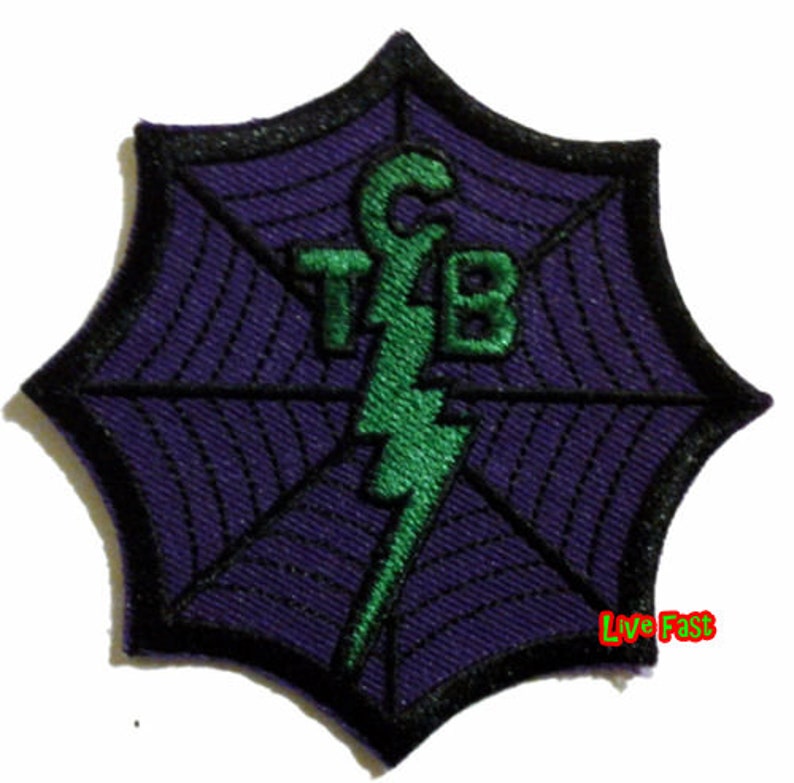 May include: Embroidered patch with a purple spiderweb design, black border, and green lightning bolt. The letters "TFB" are above the lightning bolt. The text "Live Fast" is in the lower right corner.