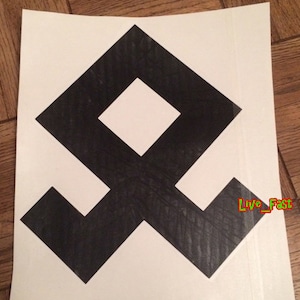 May include: Black and white geometric symbol with a square in the center. The symbol is on a white background.