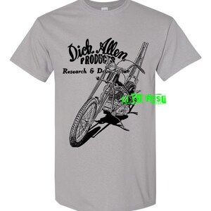 May include: A grey t-shirt featuring a black and white illustration of a motorcycle and the text "Dick Allen Products Research & Development".