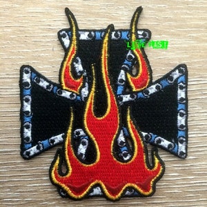 May include: Black and blue embroidered patch with a red and yellow flame design in the shape of a cross.