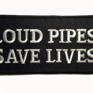 May include: Black embroidered patch with white text that reads "Loud Pipes Save Lives".