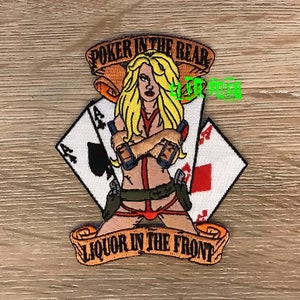 May include: An embroidered patch with a woman holding two guns, with the text "Poker in the Rear" and "Liquor in the Front" on a scroll.