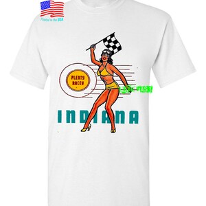 May include: White t-shirt with a graphic of a woman in a swimsuit holding a checkered flag. The graphic also includes the text "Plenty Racey" and "Indiana".