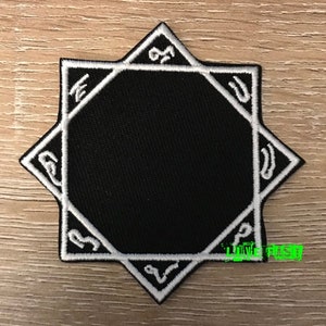 May include: Black embroidered patch with a white eight-pointed star design. The star has a circle in the center and symbols around the outer edge.