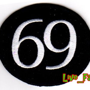 Könnte beinhalten: Ein schwarzer runder Patch mit der Nummer 69, die in Weiß gestickt ist. Der Patch hat einen weißen Umriss.