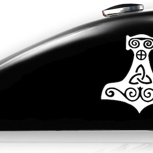 May include: A white vinyl decal of a stylized Mjolnir, Thor's hammer, with a Celtic knot design. The decal is on a black gas tank.