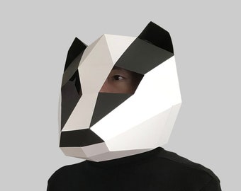 May include: A person wearing a white and black papercraft badger mask. The mask is geometric and has a 3D effect.