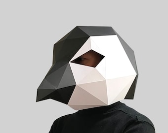 May include: A person wearing a black turtleneck sweater and a black and white geometric paper mask that resembles a bird's head.