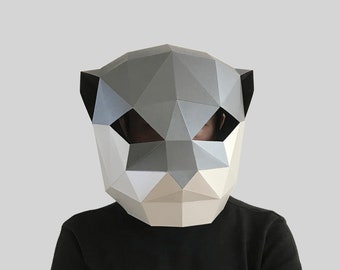 May include: A person wearing a gray and white paper mache animal mask. The mask is geometric and has a pointed snout.
