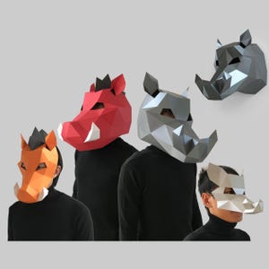 May include: Geometric paper masks in the shape of warthogs and rhinos. The masks are various colors, including red, orange, silver, and white. The masks are worn by people wearing black shirts.