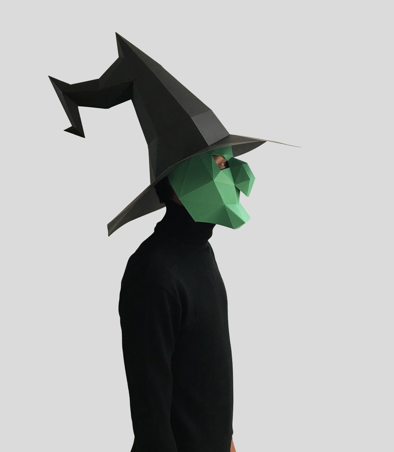 May include: A person wearing a black witch hat and a green witch mask. The hat has a long, pointed brim and a curved, pointed top.