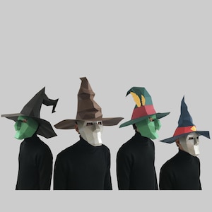 May include: Four papercraft masks of different characters wearing pointed hats. The masks are all white with different colored details. The hats are brown, green, blue, and black.