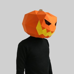 Peut inclure: Une personne portant un masque de citrouille en papier m&acirc;ch&eacute; avec un visage effrayant. Le masque est orange avec des dents et des yeux jaunes.