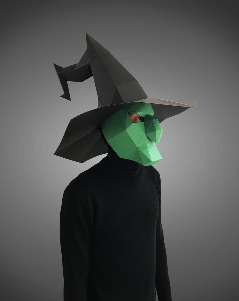 May include: A person wearing a black turtleneck and a green witch mask with a black pointed hat.