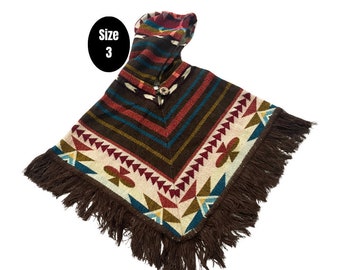 Könnte beinhalten: Ein braunes Kapuzenponcho mit einem bunten geometrischen Muster und Fransen. Das Poncho hat einen Knopfverschluss und der Text "Größe 3" ist sichtbar.