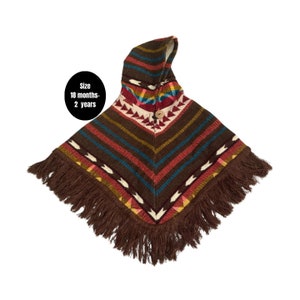 May include: A brown hooded poncho with a colorful geometric pattern and fringe trim. The poncho is sized for 18 months to 2 years.